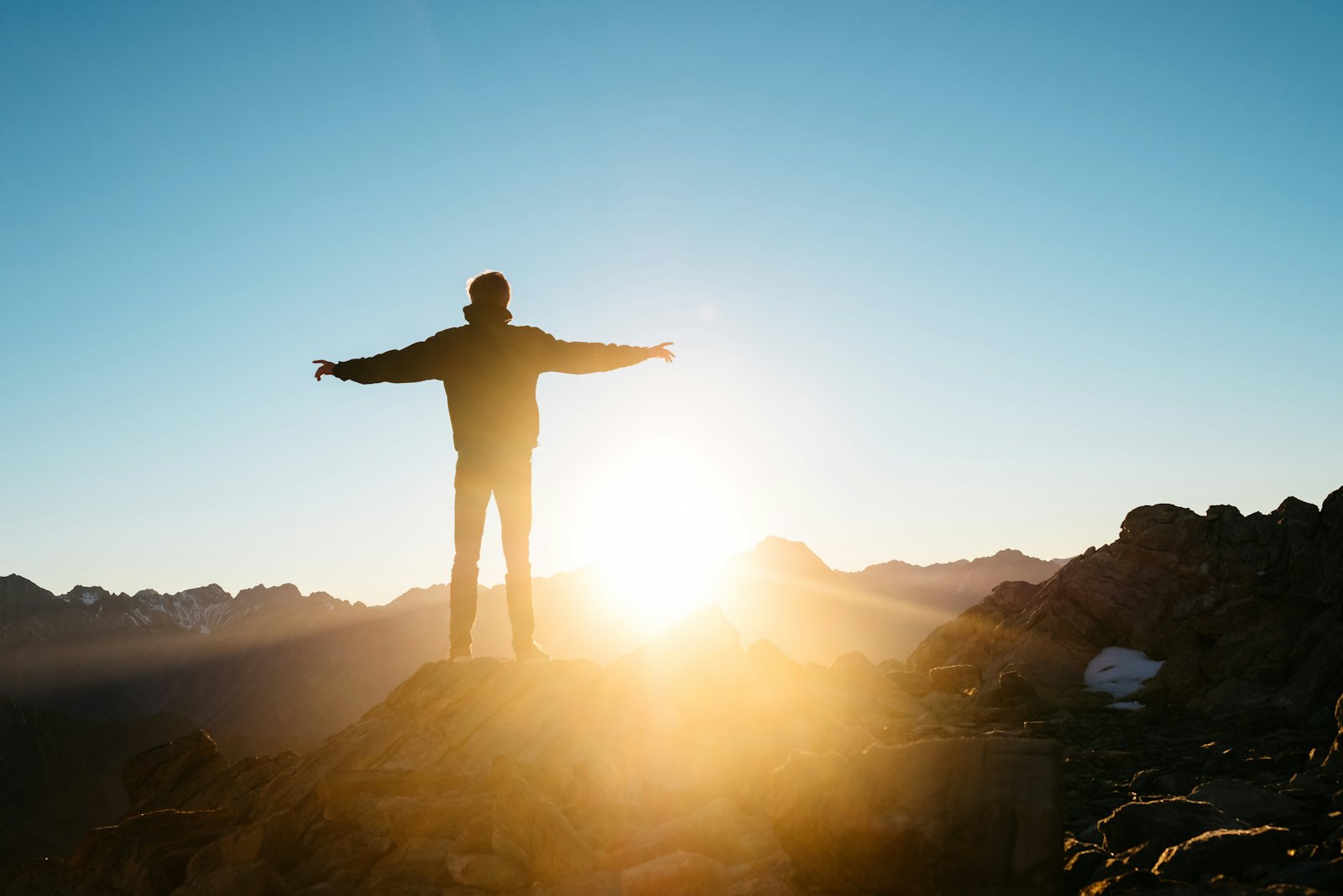 Person with arms raised in joy on a hilltop at sunset, celebrating personal growth and positive transformation